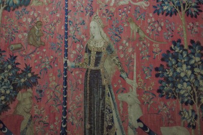 Touch - According to medieval beliefs, the unicorn can only be tamed by a young virgin. To evoke touch, the lady touches the horn of the animal while holding the staff of a banner with her other hand. An intriguing detail is that the small animals in the tapestry all wear collars and harnesses with iron rings; a way perhaps of associating this most material and earthly of the senses with the notion of possession. For he who lets himself be touched gives himself and abandons himself. Translated from Beaux Arts magazine.