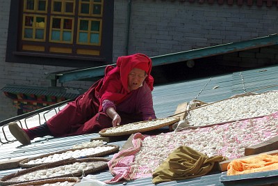 Thupten Choling Monastery: old nun watching over drying vegetables on a roof. Her job is to keep the birds away.
