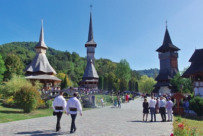 View of the eastern part of Bârsana's monastery. The monastery's actual church is in the middle of the picture; towering at 57m it is among the world's highest wooden buildings. The building to its left is an open structure used as open altar in the summer; that's where the priest was officiating, his words carried by loudspeakers with the congregation standing around and listening. The building to the right is a belfry and the entrance gate to the compound.