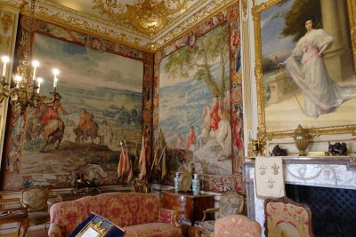 A portrait of Consuelo over the fireplace, tapestries depicting scenes of battle (battle of Malplaquet 1709 on the left and the Duke forcing the lines of Brabant on the right), some flags seized on the battle field, the red sofa and chairs with the effigy of the Sun King: typical decoration of the State rooms.