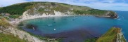 Lulworth Cove on a bright sunny June day. This photo is a panorama, click the cross on the right below the photo (or press F if viewing on a desktop) to expand it to its real size and use the bottom scroll bar to navigate through it.