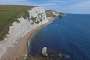 View to the east from Bat's Head onto the beach with Durdle Door visible, jutting into the sea.