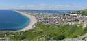 View on the town of Portland and the isthmus linking the peninsula to the mainland with Chesil Beach on the left and Weymouth Bay on the right.